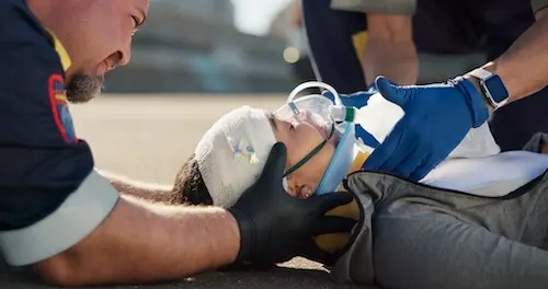 car accident victim with injuries being assisted by paramedics