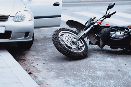 Lenoir City motorcycle accident lawyer examining crash scene with motorcycle and car on roadway