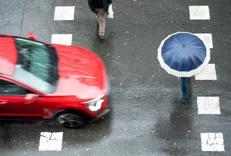 An aerial view of pedestrians crossing a wet street with an approaching car highlighting pedestrian accident trends and concerns in East Tennessee.